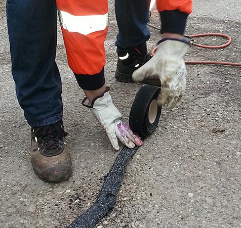 Applying bandfill overbanding to repair cracks on roads